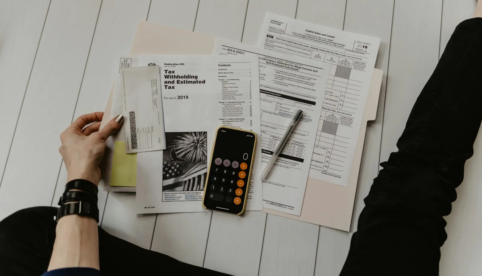 Close view of a hand reviewing paperwork beside a pen